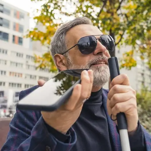 senior man with cane outdoors talking on smart phone