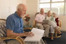 seniors in living room setting reading braille and large print