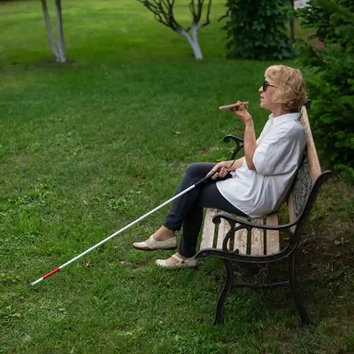senior woman on bench with cane and talking on smart phone